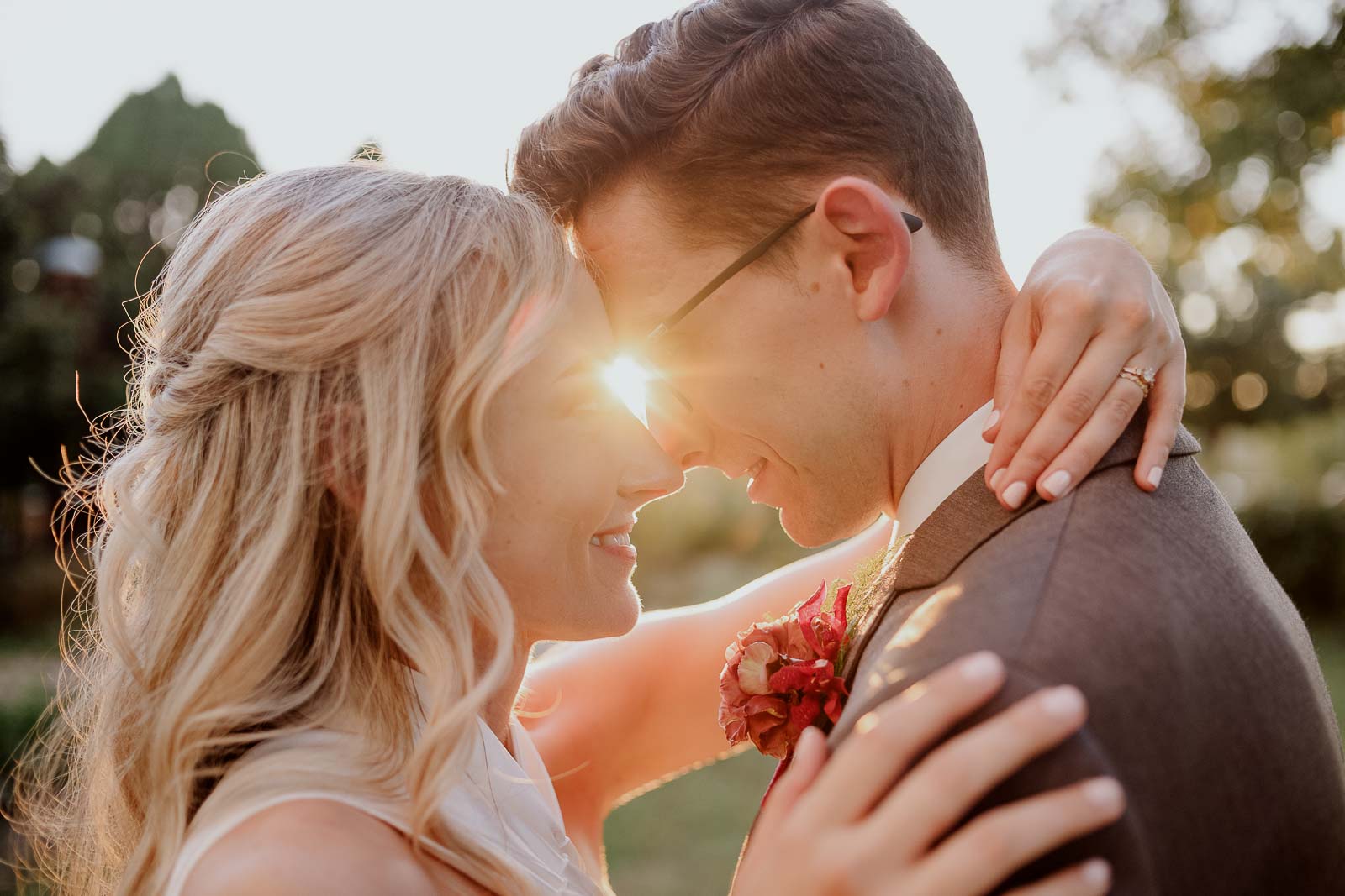 Couple portrait head to head closeup at sunset as suns rays come between them