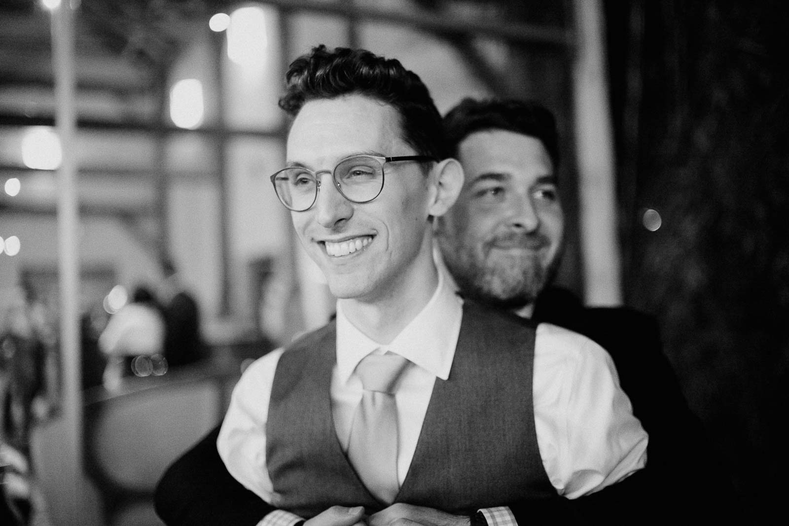 A friend bears hugs the groom at a wedding reception