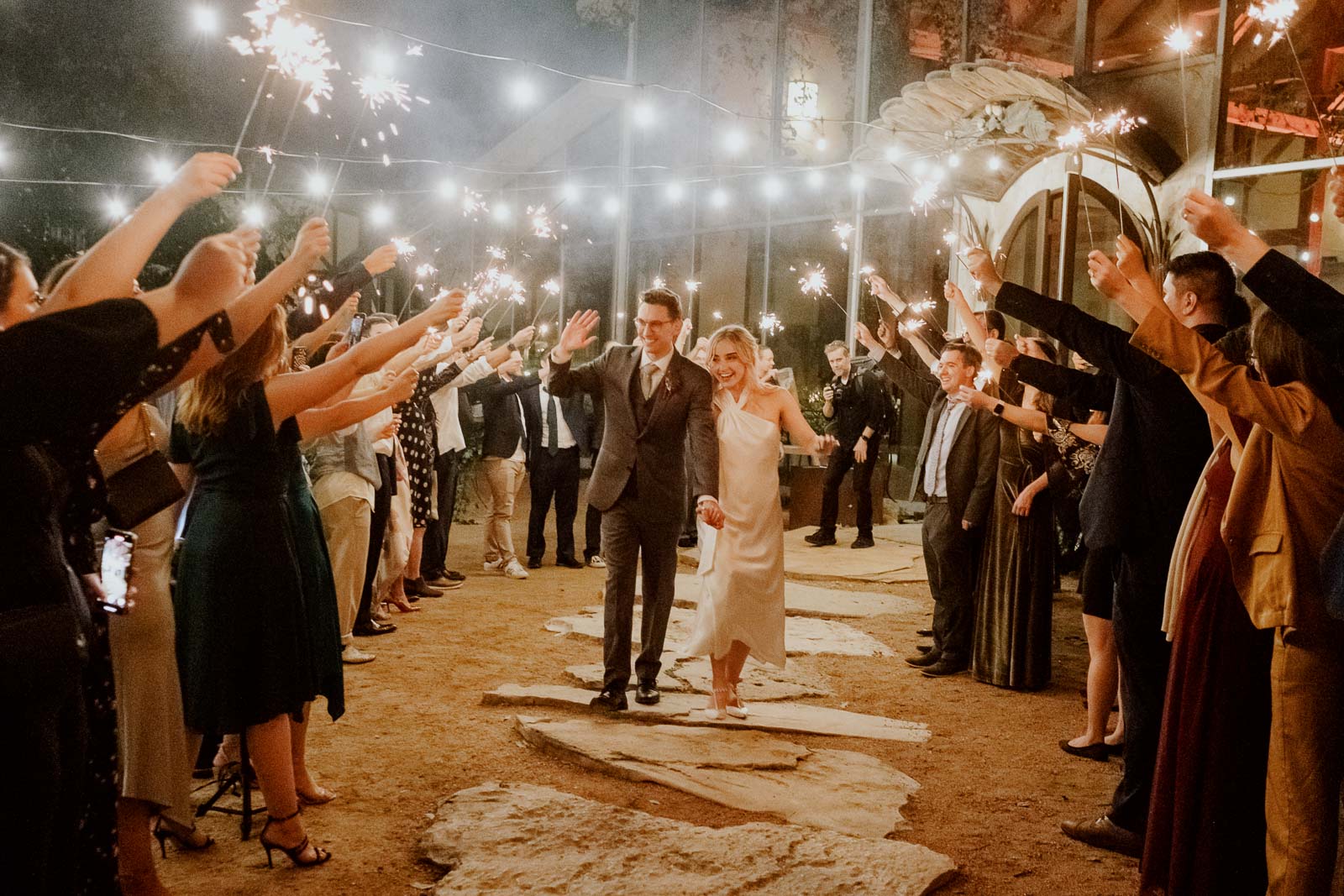 Couple depart Barr Mansion ballroom under sparklers with friends and familyin natural light