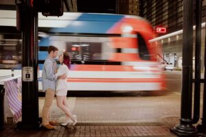 A city tram rumbles past couple's engagement session on Main Street, downtown Houston