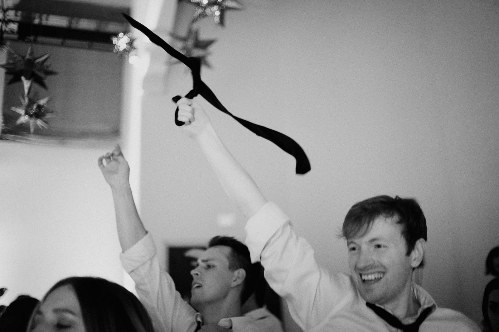 Wedding guests swirls their ties in the air at a wedding reception at the McNay