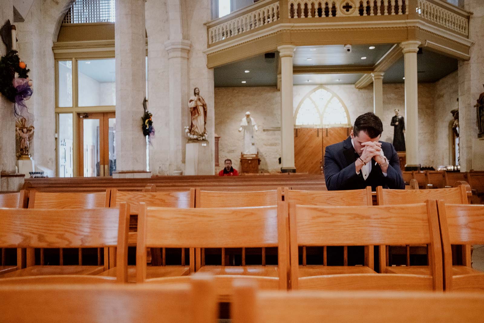The groom kneeling prays before the wedding ceremony at San Fernando Cathedral