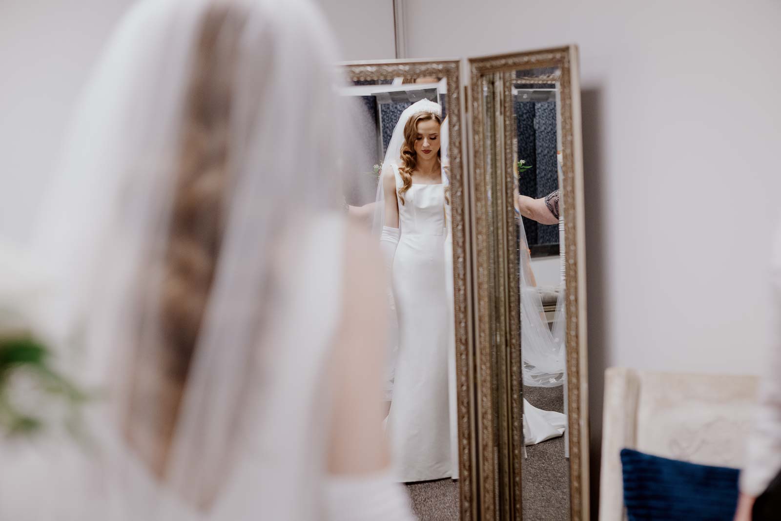 A bride checks herself in a full length mirror