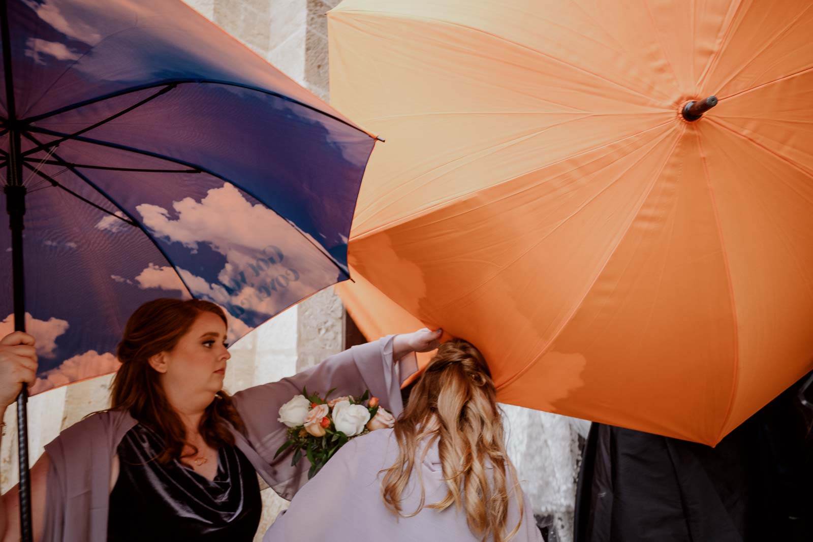 Bright colored umbrellas protect the bride as she enters the cathedral