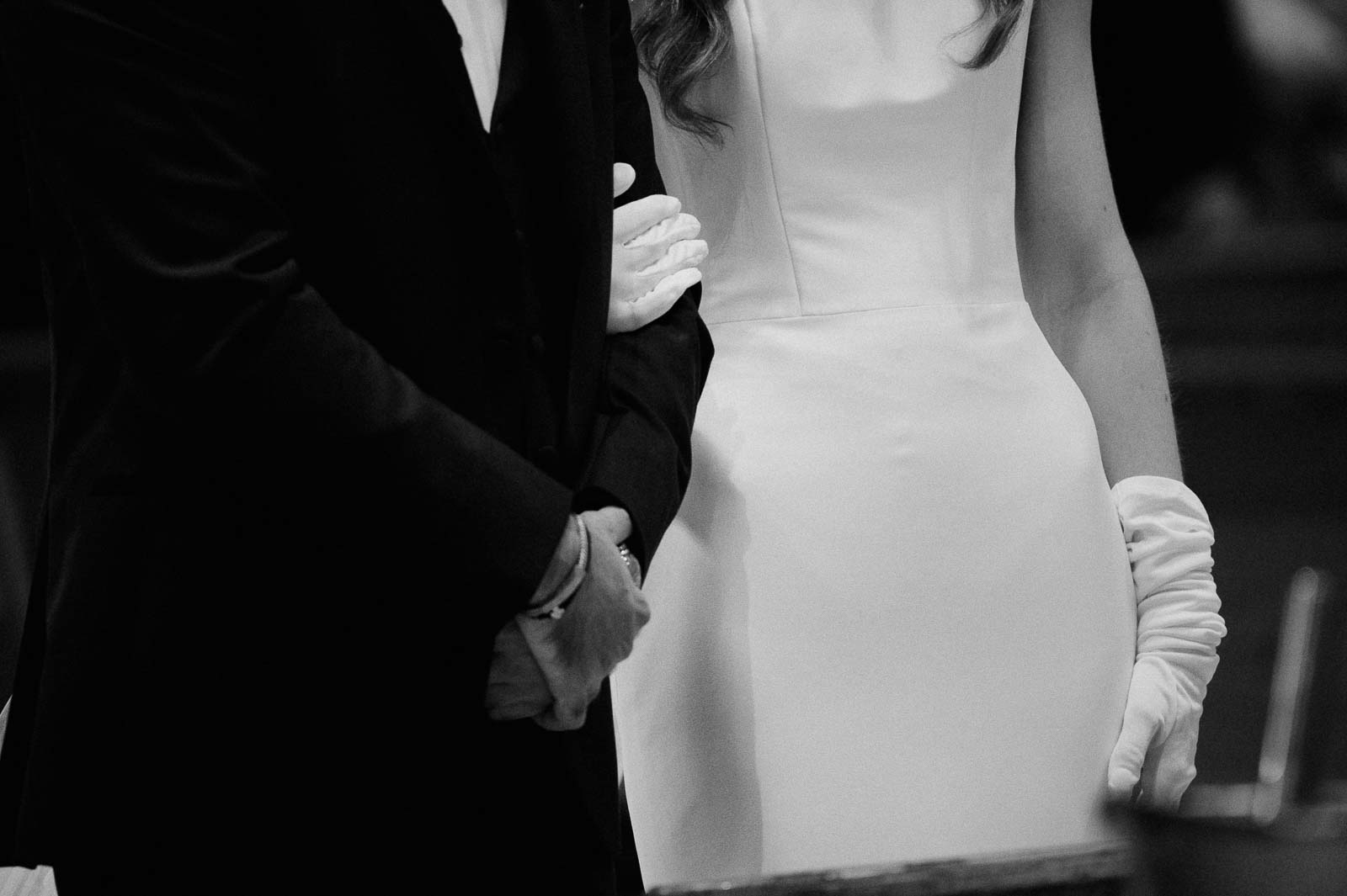 Close up of brides white gloves with the groom