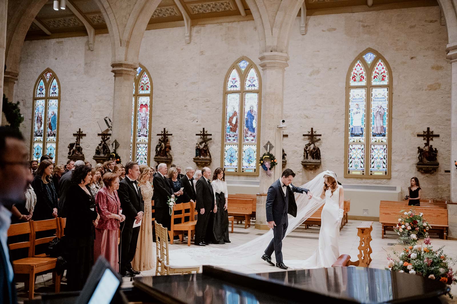 A wide angle shows the groom assisting the brides veil during a wedded ceremony 