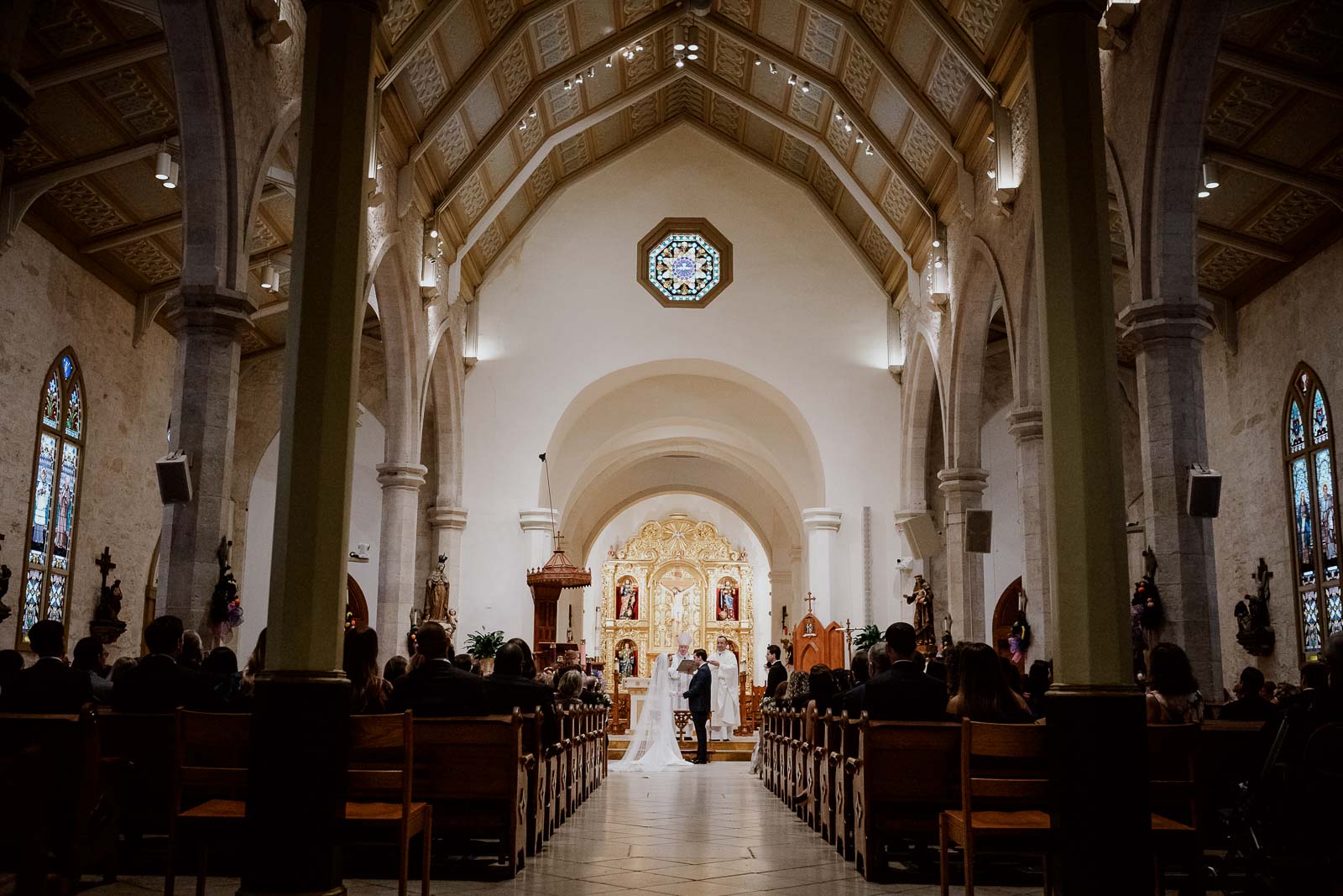 A wide angle taken from the back of the church show a couple making their wedding vows