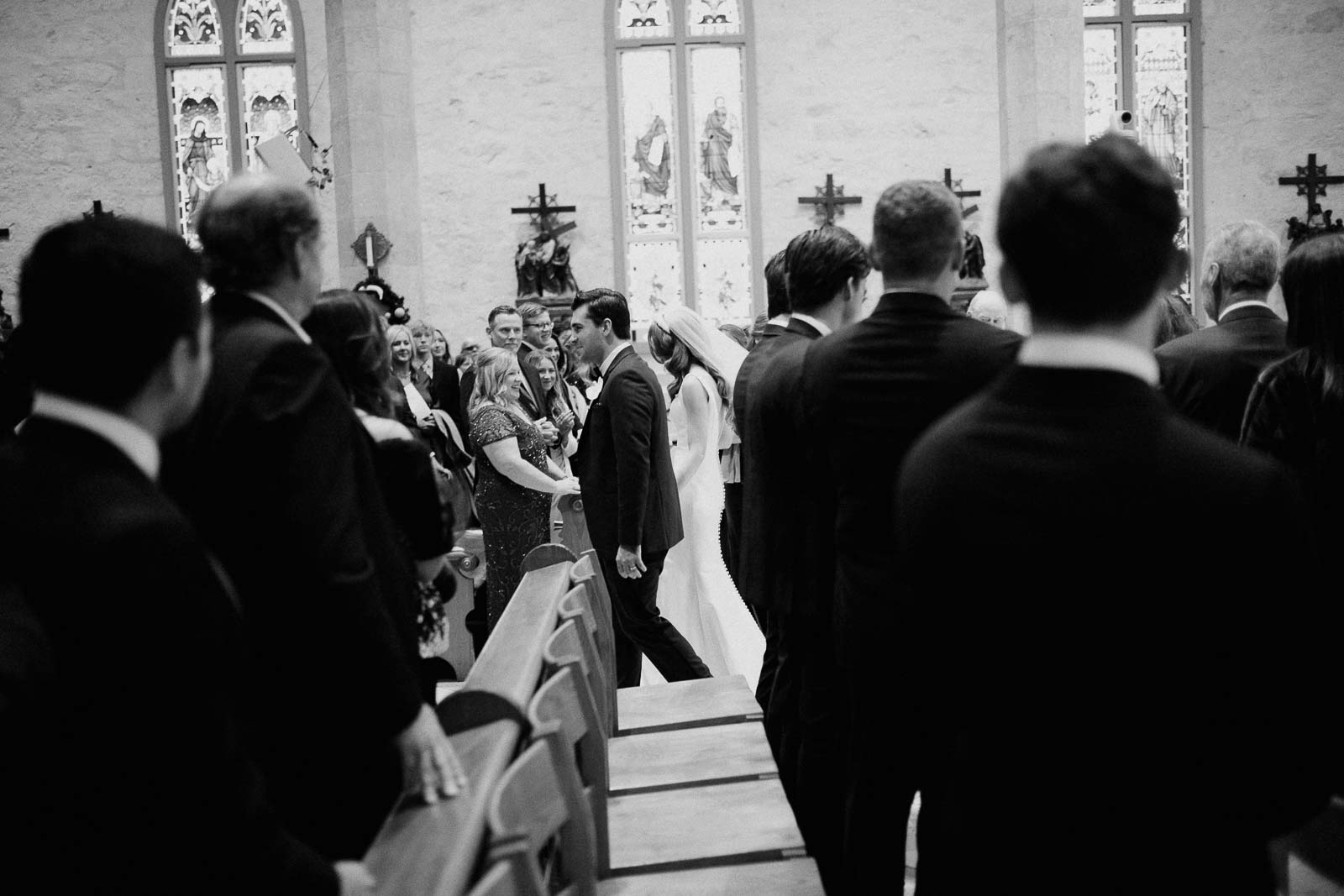 A side view from a church pew as the newly wedded couple are applauded by church attendees