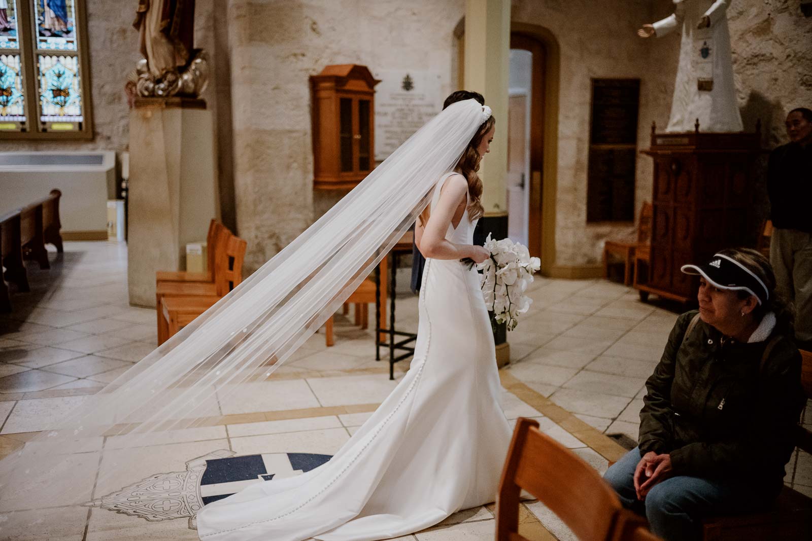 The brides veil stretching out behind her as the couple reach the end of church aisle