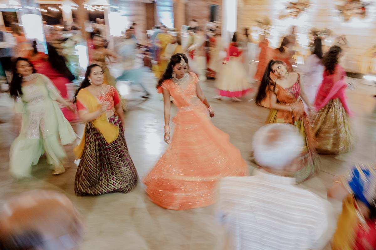 A Indian bride at a sangeet glides across the floor, at a traditional pre-wedding event in Indian culture that involves music, dance, and food. It's a time for family and friends to come together and celebrate the upcoming wedding festively and joyously. L1001716