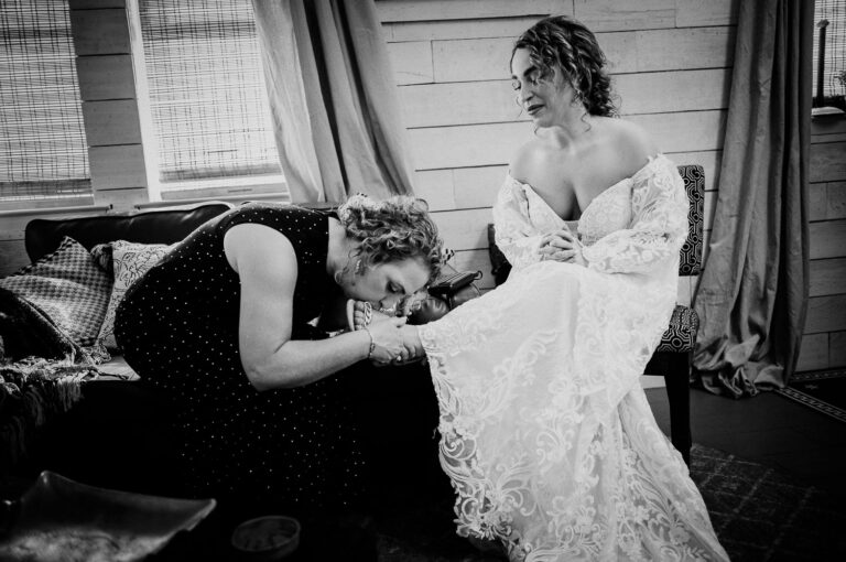 Mother of the bride kisses her foot in a quiet moment before the wedding ceremony at Elm Pass Woods in Texas - L1004684 Edit