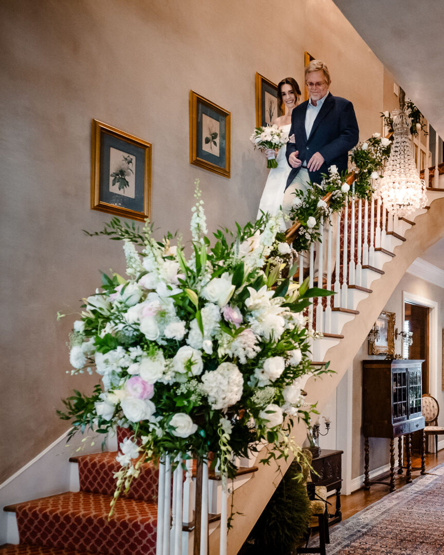 Elegant Houston Elopement | Caroline+George | Houston, Texas 13 Bride and father of the bride descending staircase adorned with flowers.