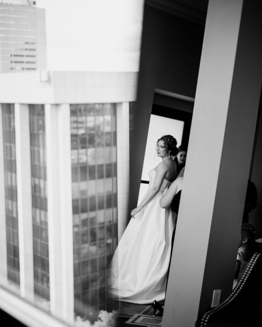 Bride preparing near window reflection.