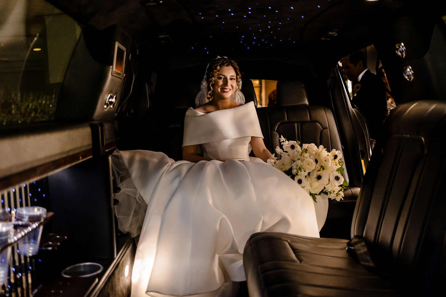 Bride in limousine with bouquet.