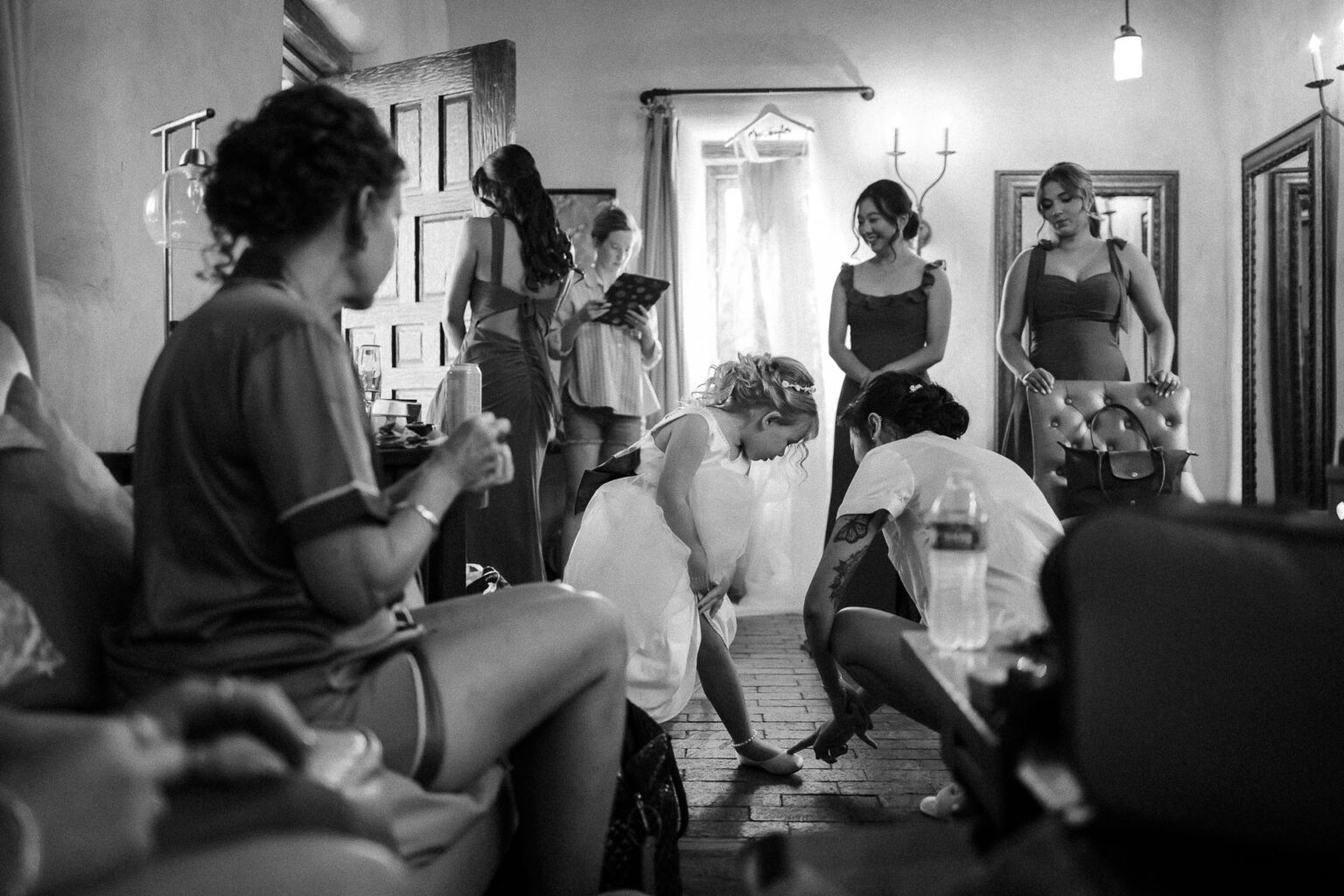 Bridal preparations with bridesmaids assisting.