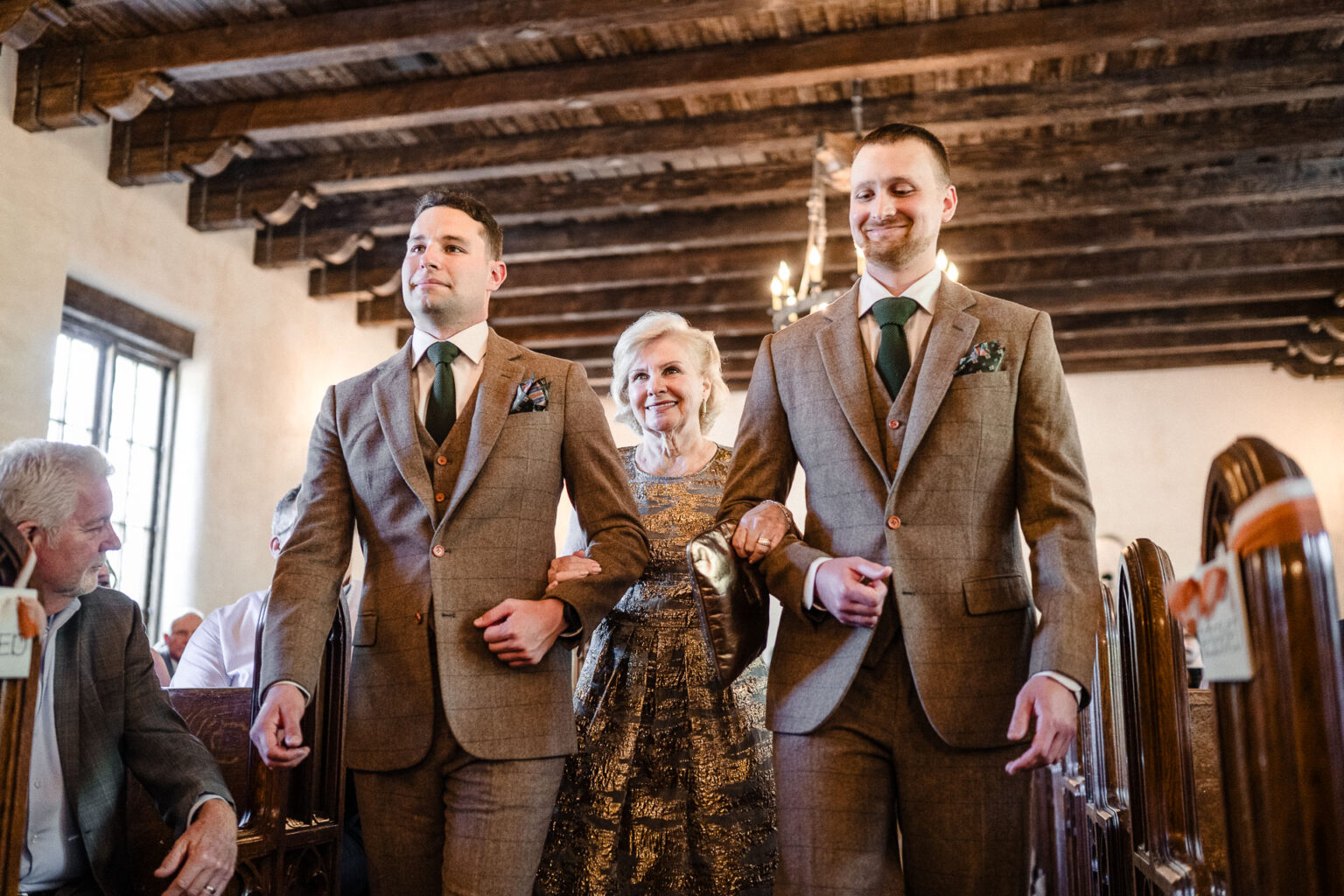Two men escorting a woman down aisle.