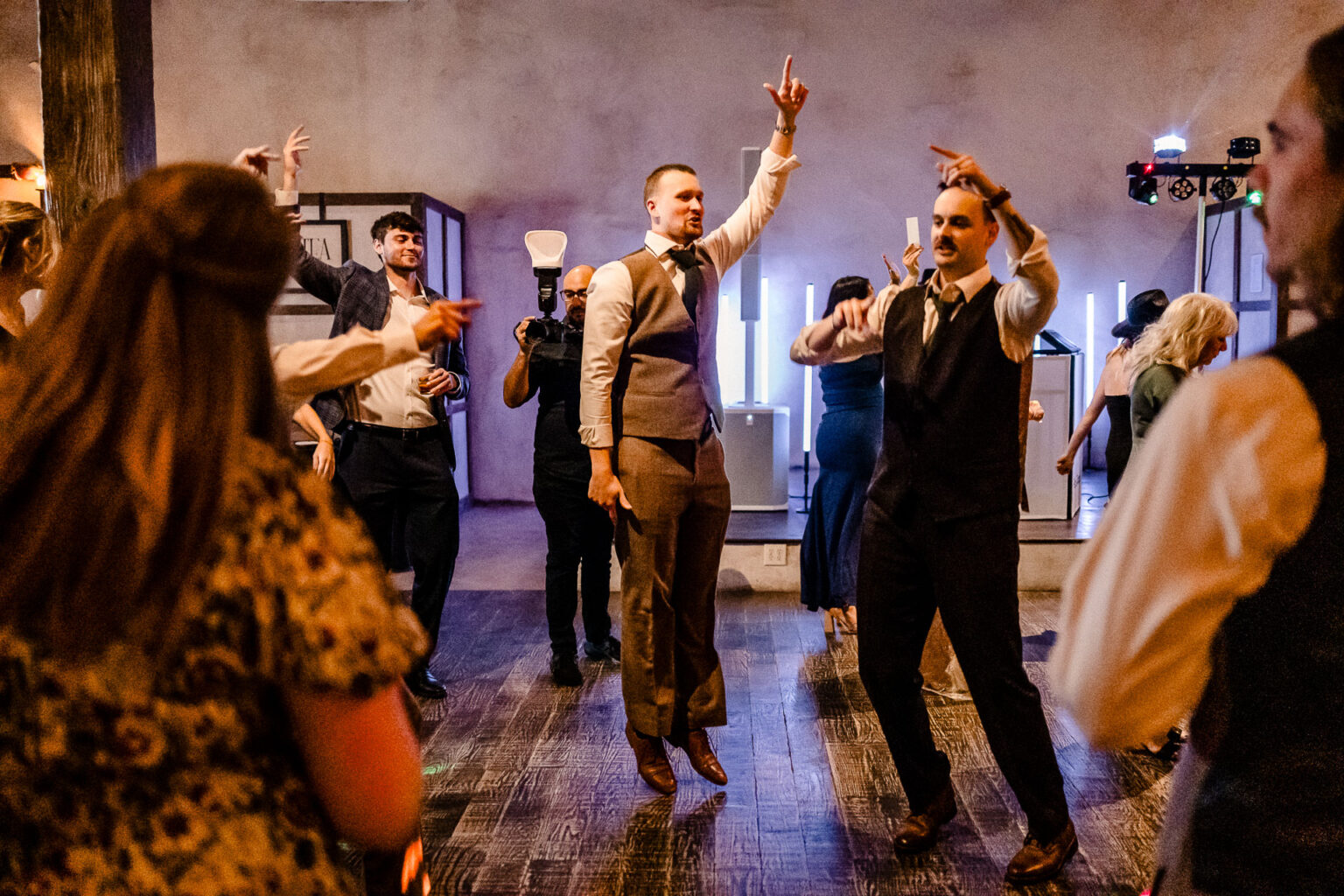Guests dancing joyfully at wedding reception.