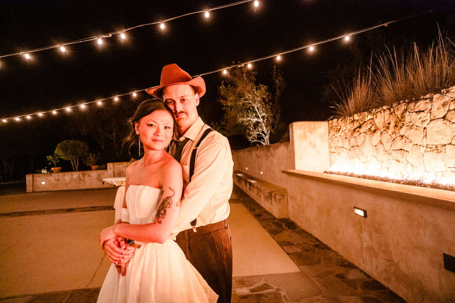 Couple embracing under string lights.