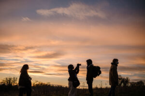 Documentary & Observational Still Photography 13 Silhouettes of crew and talent standing in a field at sunset during an outdoor shoot