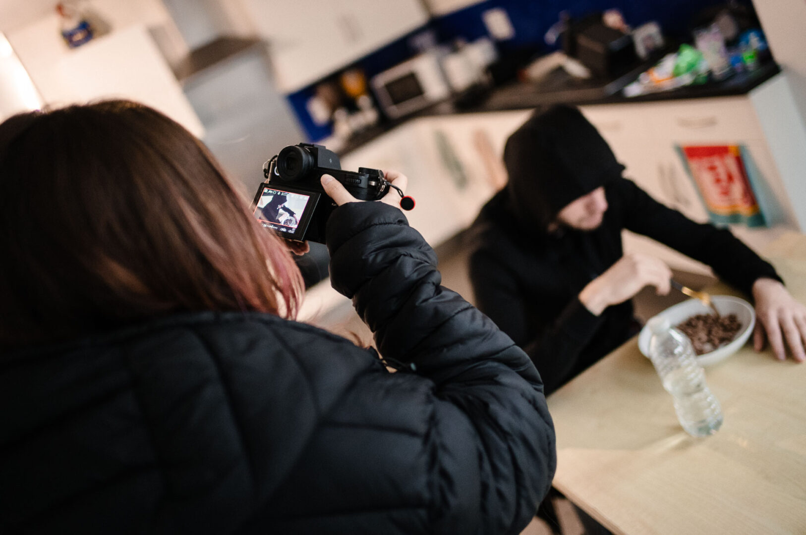 Documentary & Observational Still Photography 10 Over-the-shoulder view of a photographer shooting talent at a table during an interior set setup