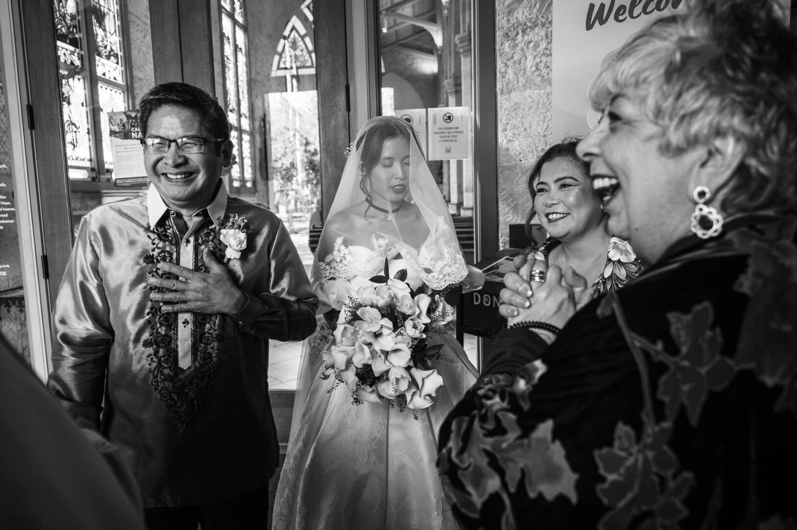 Just before the ceremony at San Fernando Cathedral, everyone gathered in the annex, waiting to begin. The bride stood quietly under her veil, focused and calm. Next to her, her parents laughed with the priest, lightening the mood.