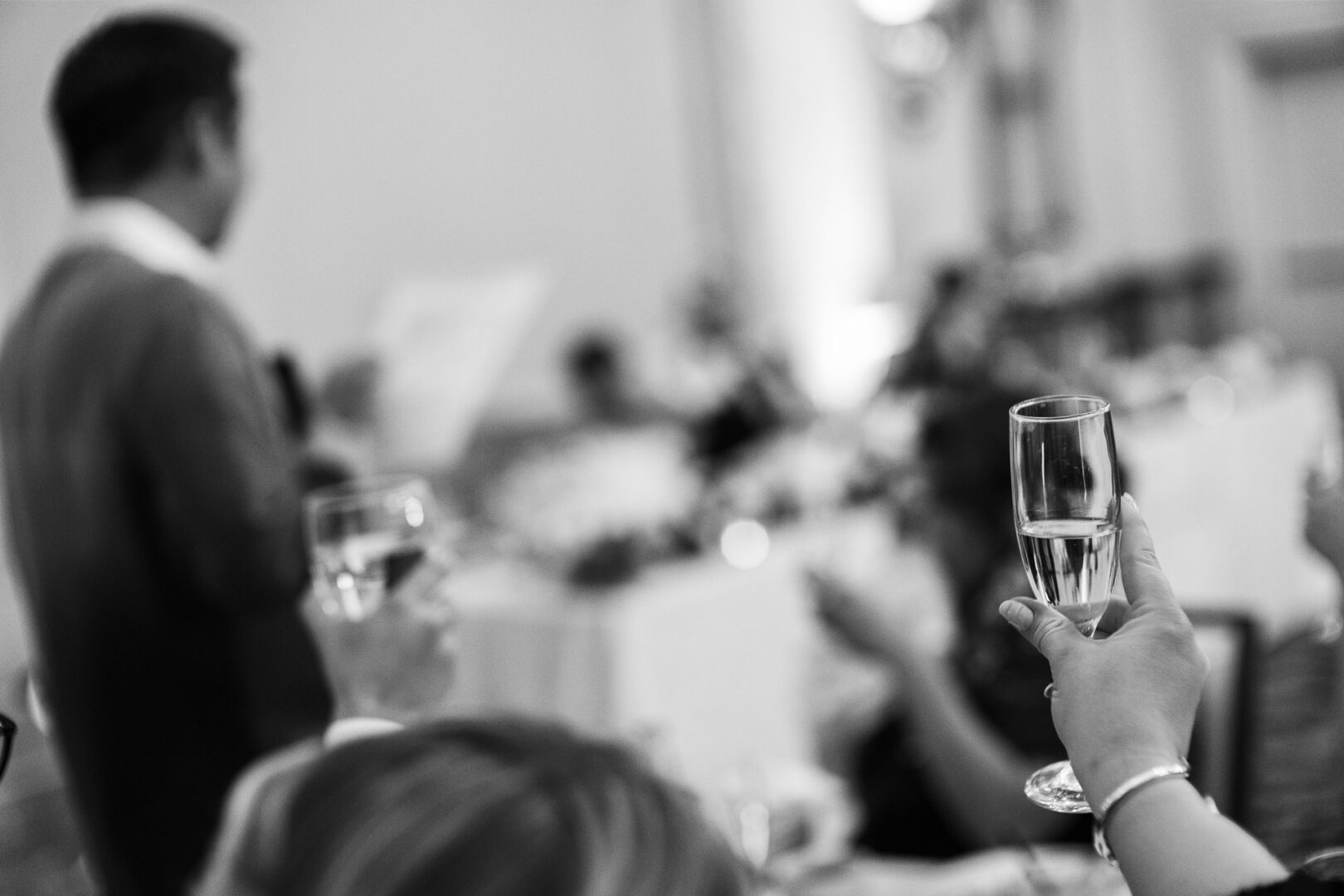 Noreena & Robert's Elegant Wedding at San Fernando Cathedral 52 Celebration with toasting glasses in focus.