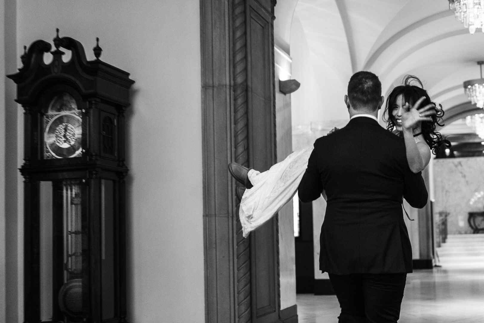 Groom carrying bride in elegant venue.