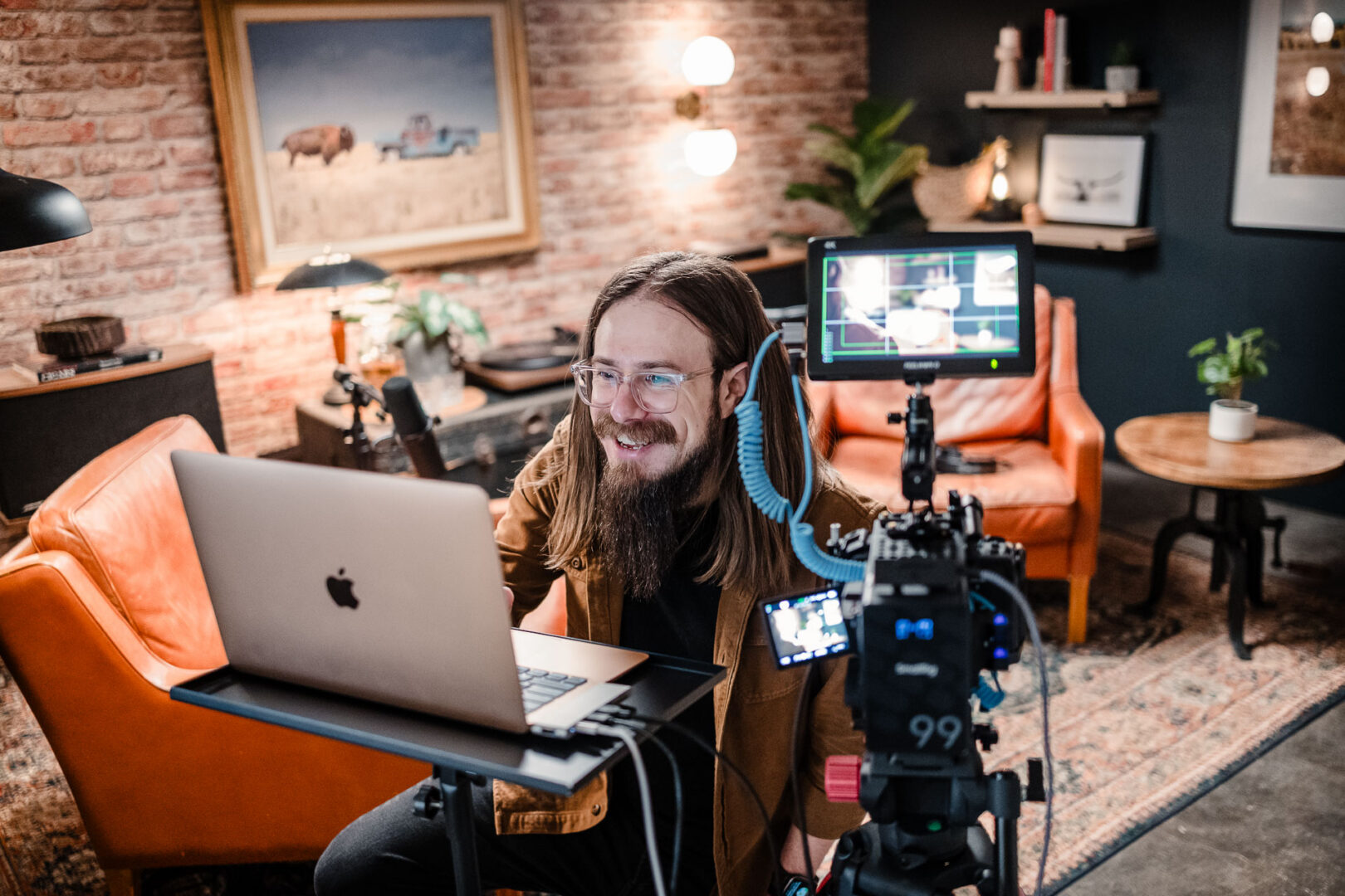 Documentary & Observational Still Photography 4 Behind-the-scenes production still of an interview setup with camera on tripod, laptop monitor, and talent seated on a lit studio set.