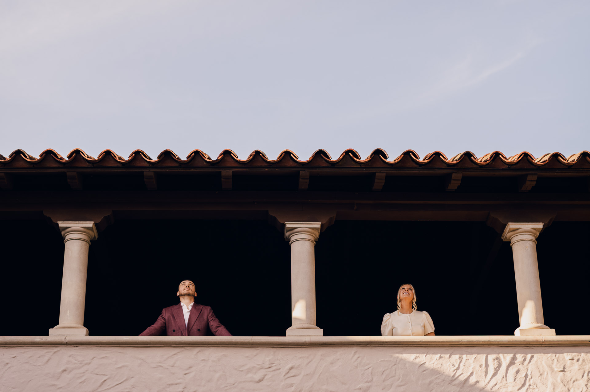 Couple standing on balcony, looking up.