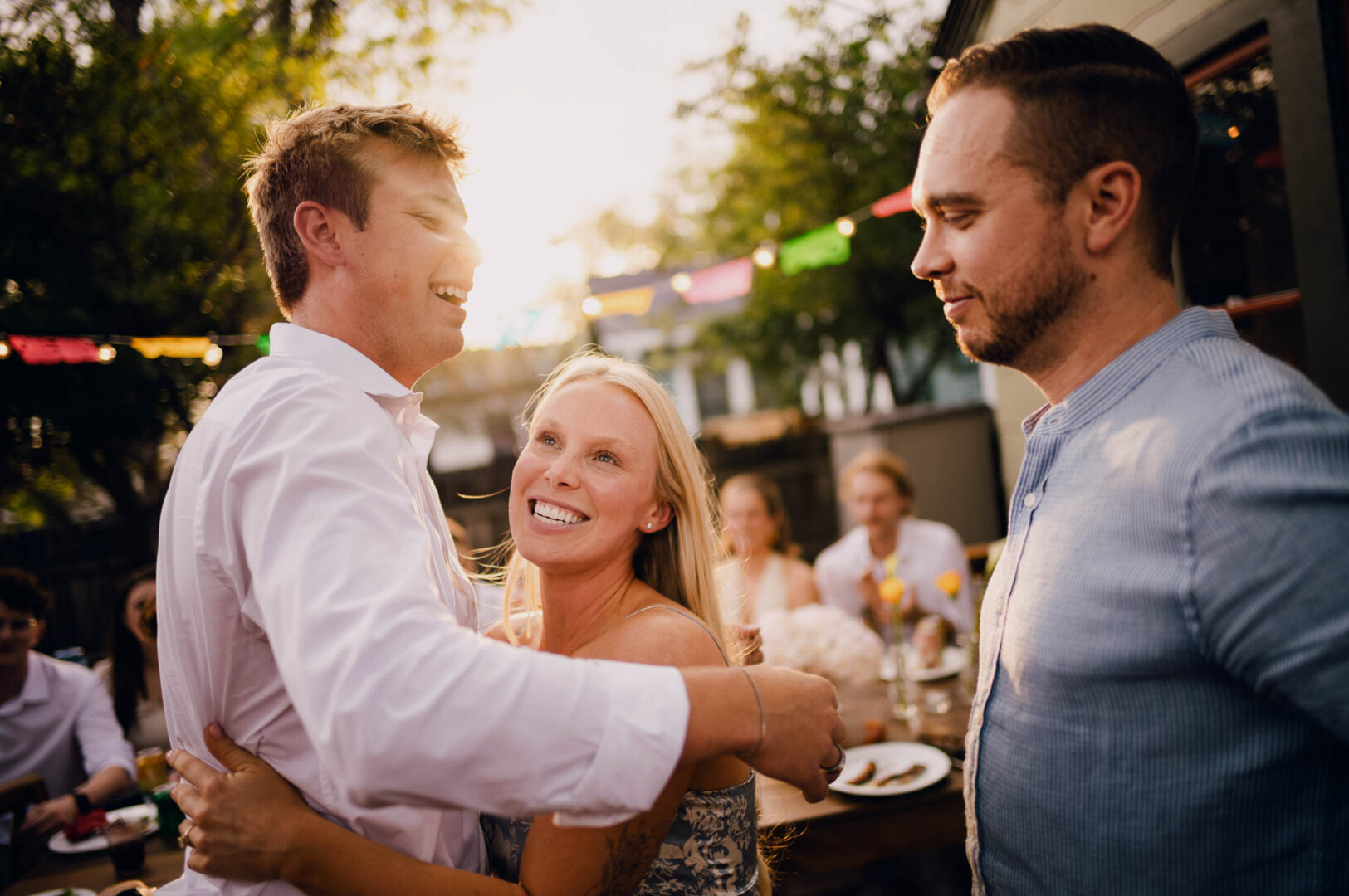 Candid hug between wedding guests during an intimate outdoor reception.