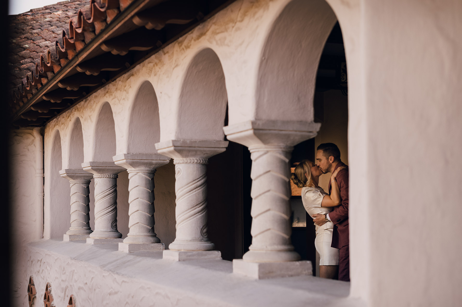 Couple embracing under architectural arches.