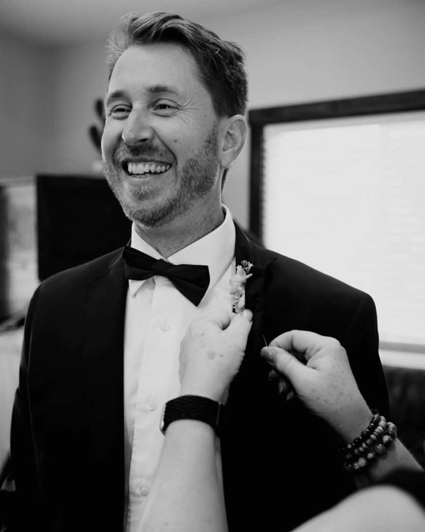 Vibrant Spring Wedding at Shiraz Gardens in Bastrop 6 Black and white candid portrait of the groom adjusting his tuxedo before the wedding ceremony in Bastrop, Texas.