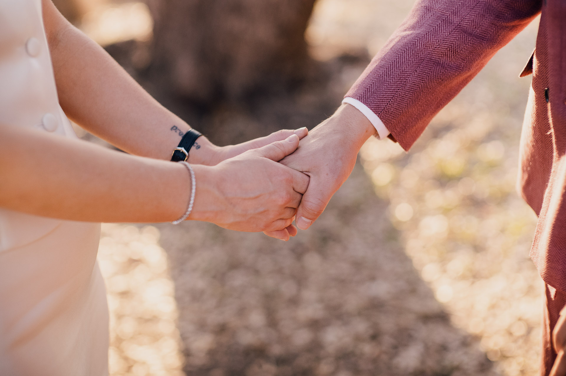 Couple holding hands outdoors, intimate moment.