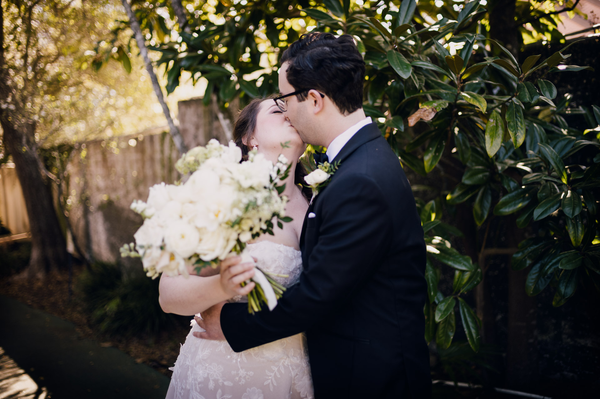 Oak Tree Ceremony & Candlelit Reception at The Houstonian 10 Groom kissing the bride on the cheek during an outdoor portrait at The Houstonian Hotel.