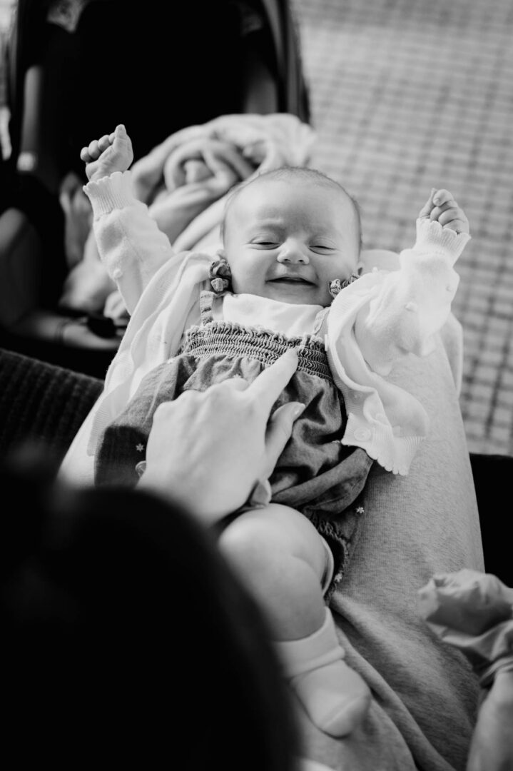 Black and white candid photo of a smiling baby during the wedding day.