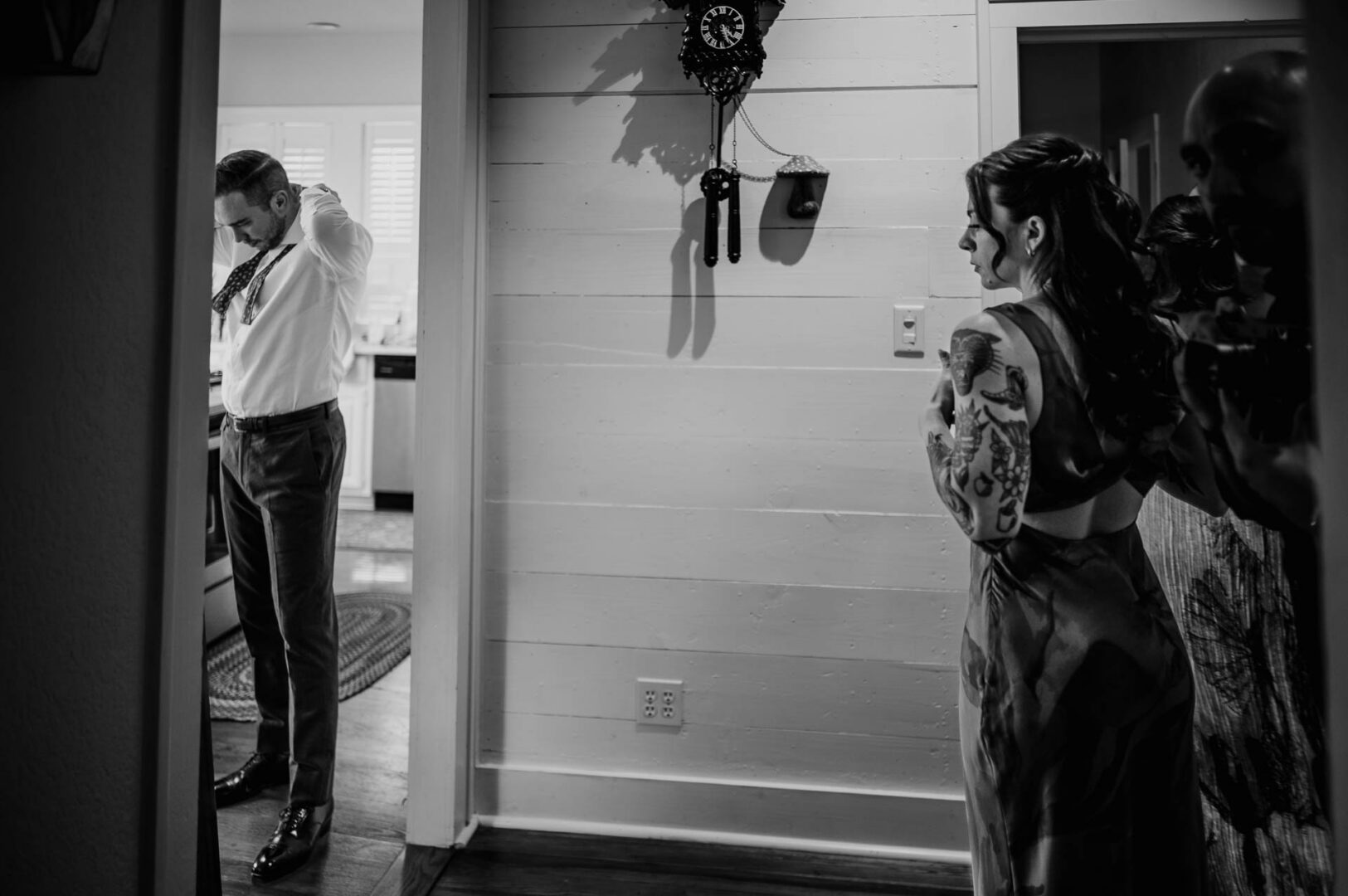 Black and white candid wedding photo of guests gathered outside a private home.