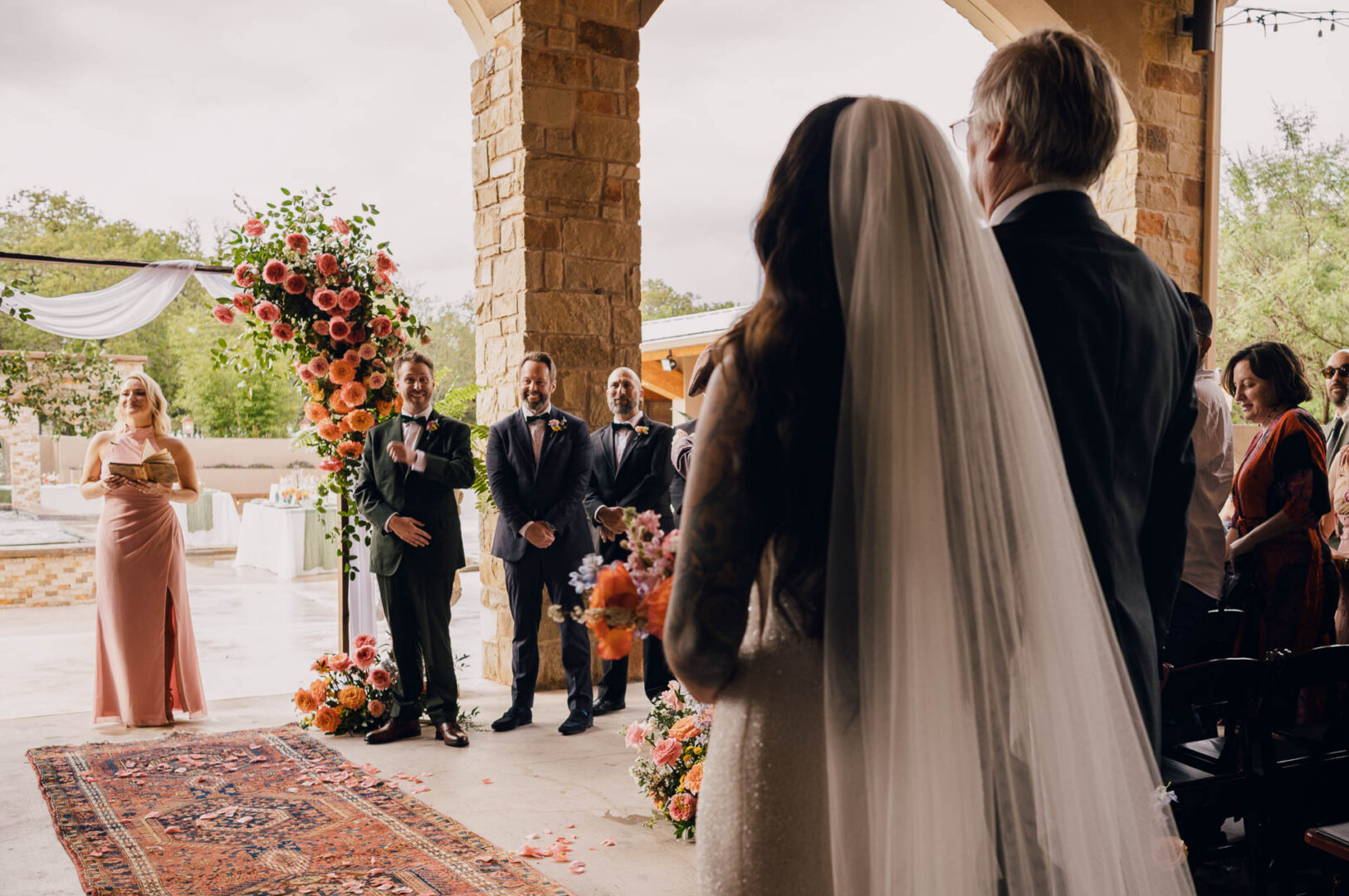 Vibrant Spring Wedding at Shiraz Gardens in Bastrop 23 Documentary wedding photograph of the bride entering the ceremony space at Shiraz Gardens.