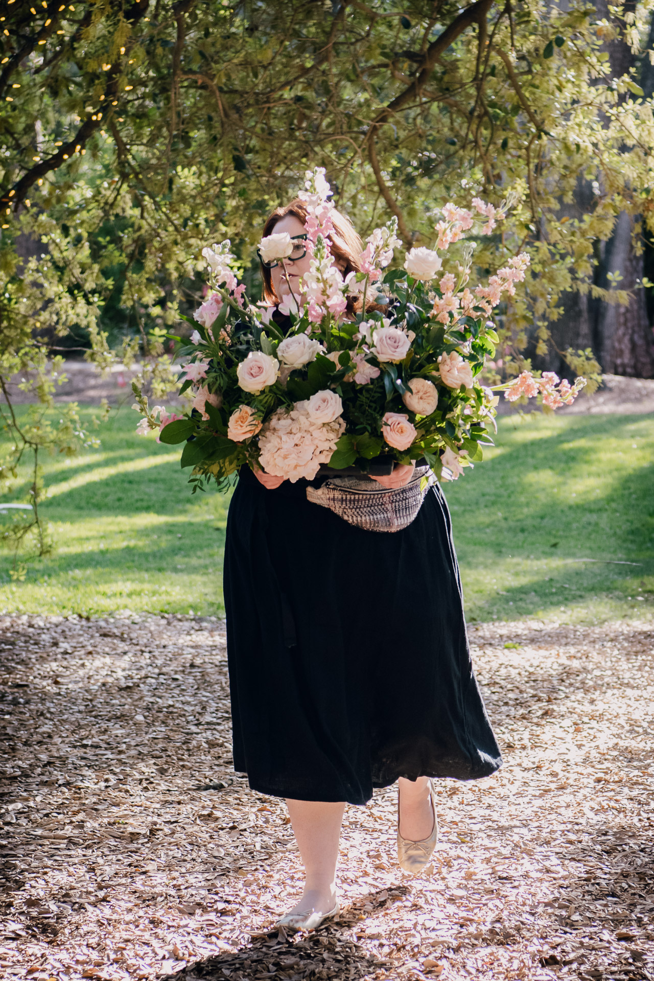 Oak Tree Ceremony & Candlelit Reception at The Houstonian 20 Wedding bouquet held in front of a dark dress outdoors at The Houstonian Hotel.