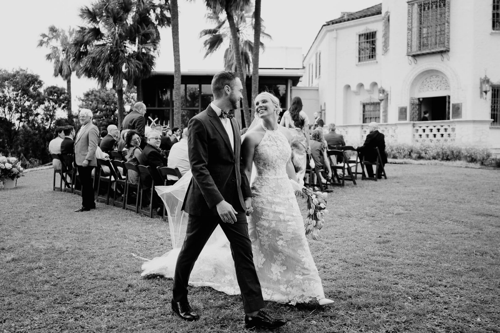 Black and white candid photo of the bride and groom walking together after the ceremony.