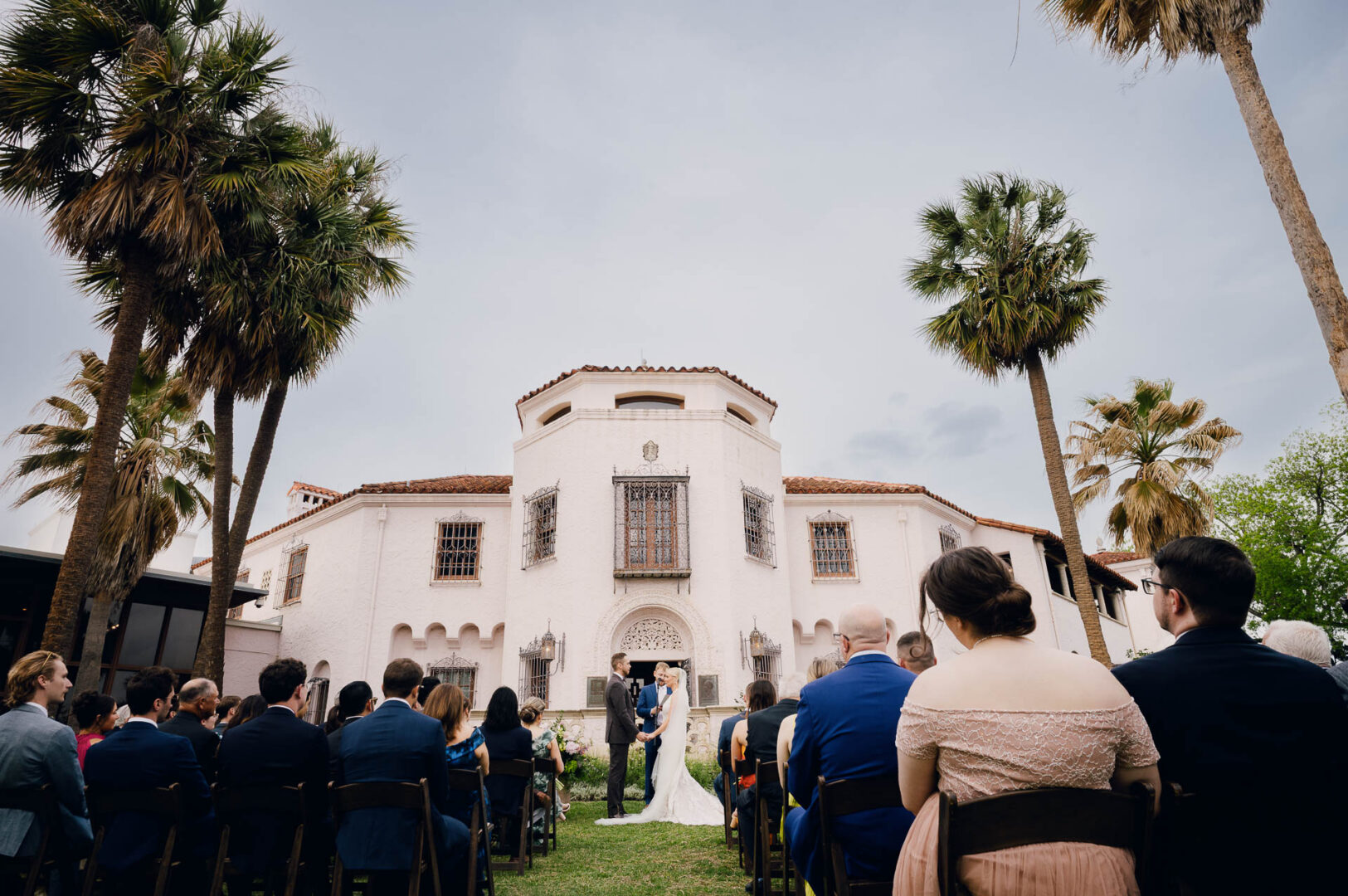 Wide view of an outdoor wedding ceremony at a historic building.