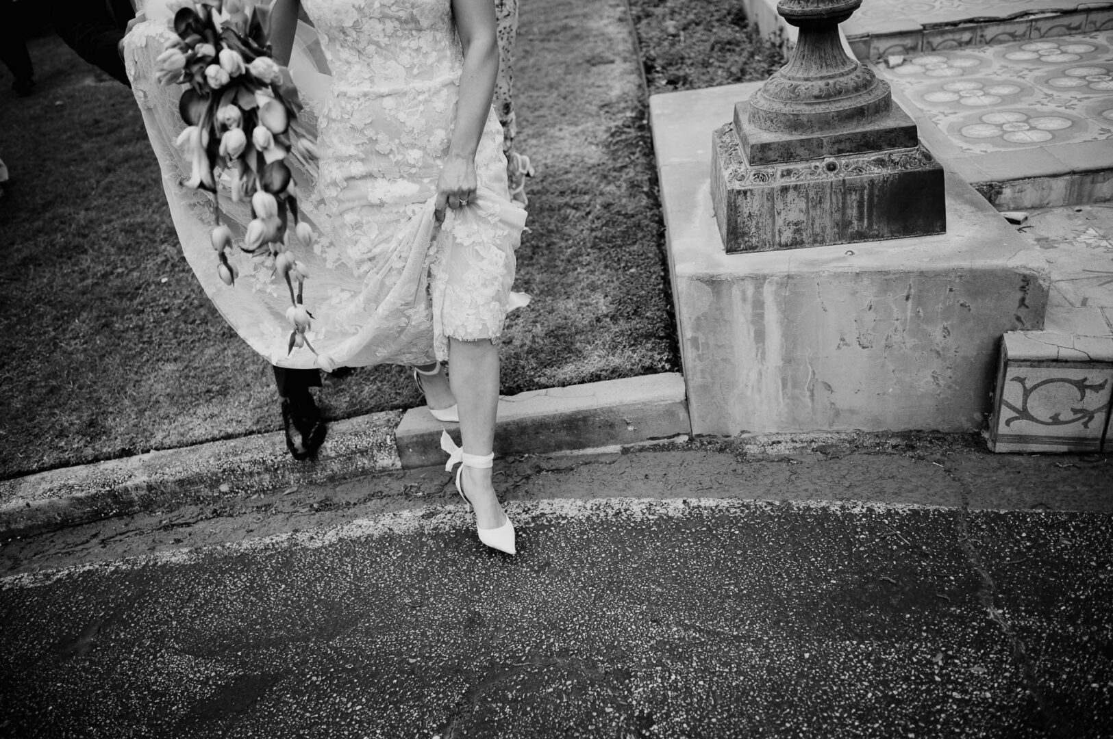 Black and white detail of the bride walking in her wedding dress.