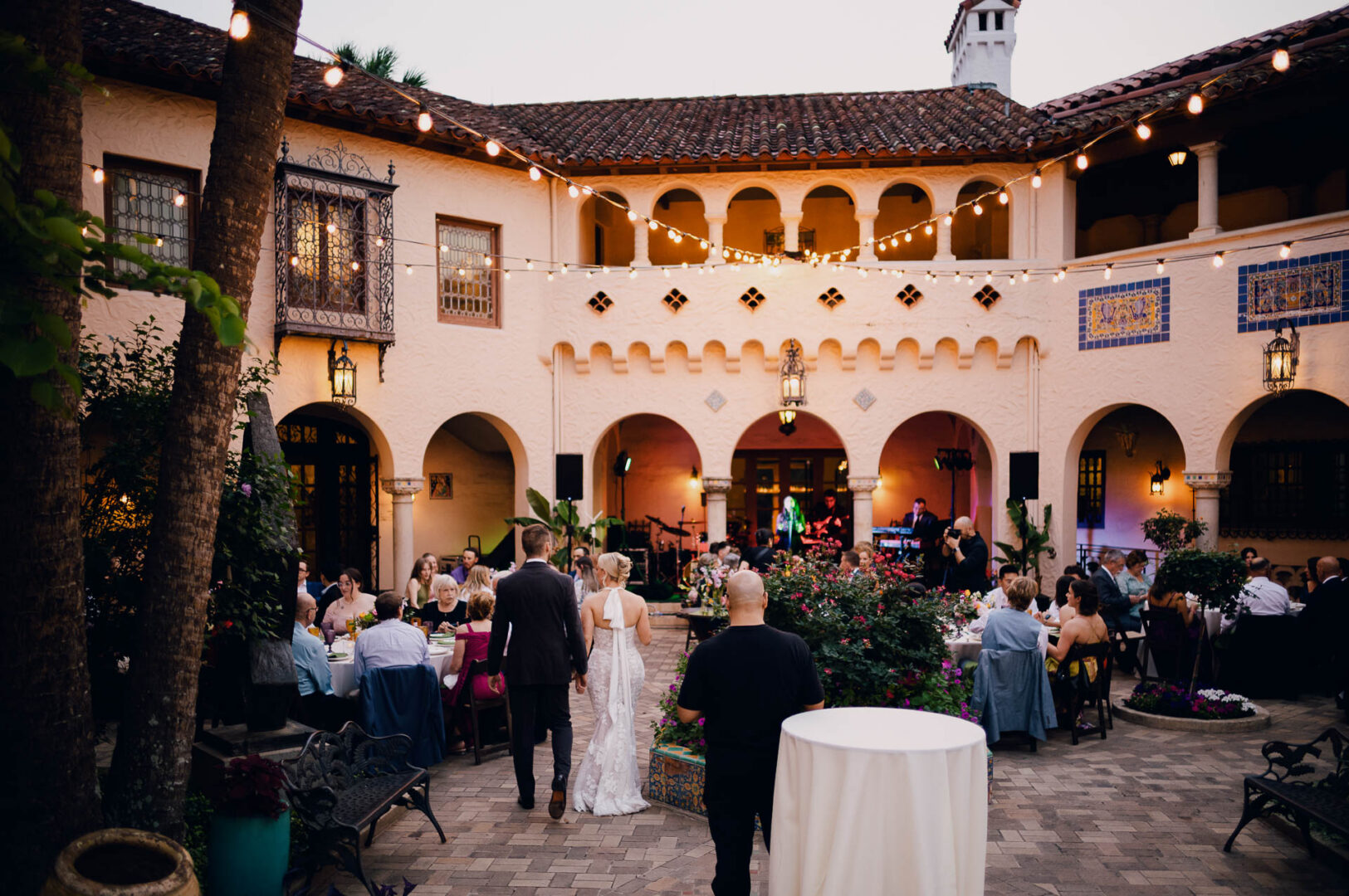 Wide view of guests gathered for an evening wedding reception in a historic venue.