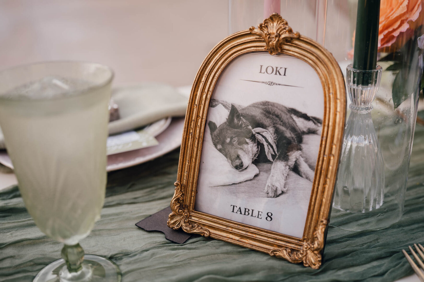 Vibrant Spring Wedding at Shiraz Gardens in Bastrop 45 Wedding detail photo of a framed illustration and glassware on a reception table at Shiraz Gardens in Bastrop, Texas.