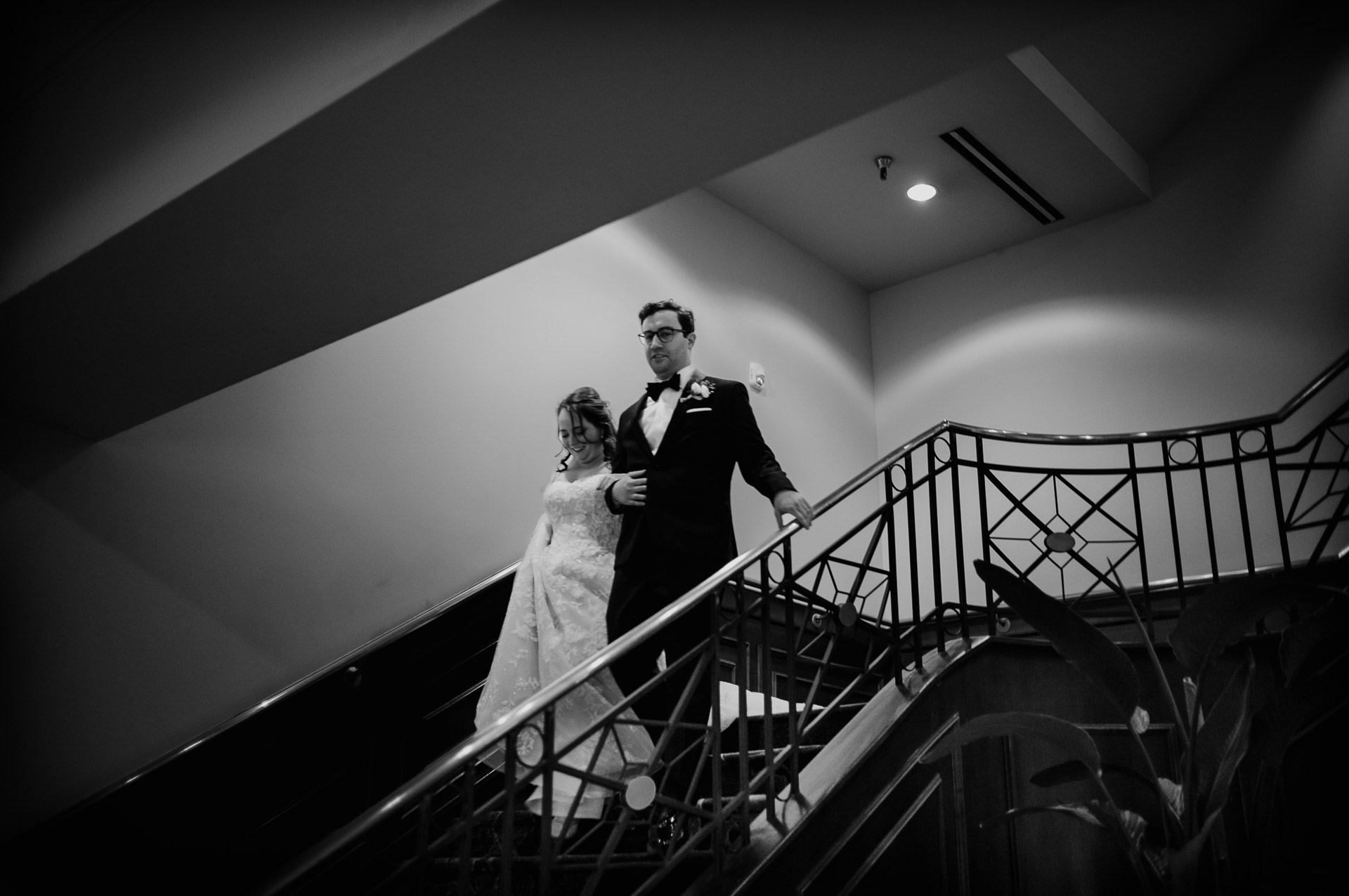 Oak Tree Ceremony & Candlelit Reception at The Houstonian 39 Bride and groom descending a staircase at The Houstonian Hotel in Houston.