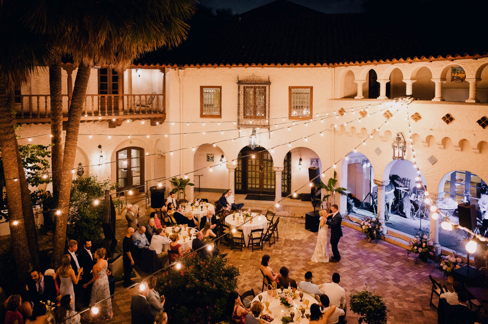 Historic courtyard wedding reception at the McNay Art Museum with round tables, string lights, and evening atmosphere.
