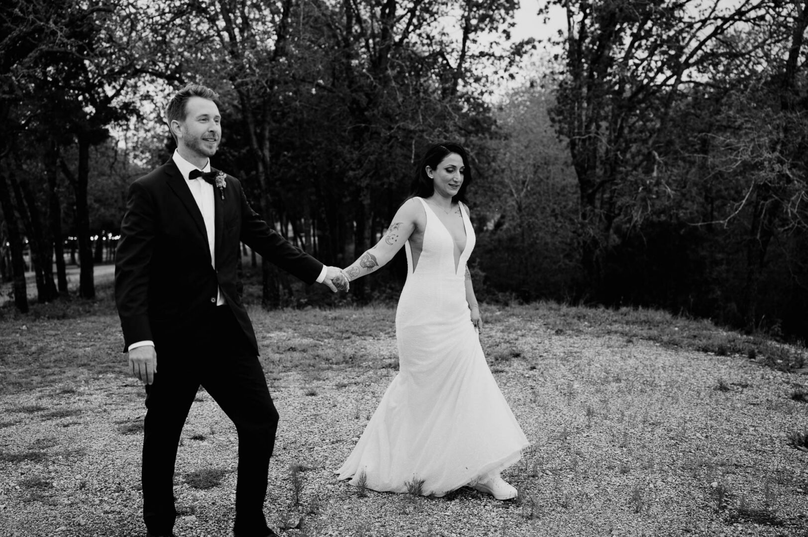 Vibrant Spring Wedding at Shiraz Gardens in Bastrop 56 Black and white documentary wedding portrait of the bride and groom walking together outdoors at Shiraz Gardens in Bastrop, Texas.