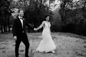 Vibrant Spring Wedding at Shiraz Gardens in Bastrop 41 Black and white documentary wedding portrait of the bride and groom walking together outdoors at Shiraz Gardens in Bastrop, Texas.