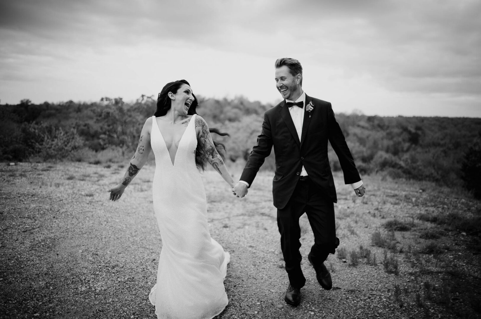 Vibrant Spring Wedding at Shiraz Gardens in Bastrop 58 Black and white documentary wedding photo of the bride and groom walking hand in hand after the ceremony at Shiraz Gardens in Bastrop, Texas.