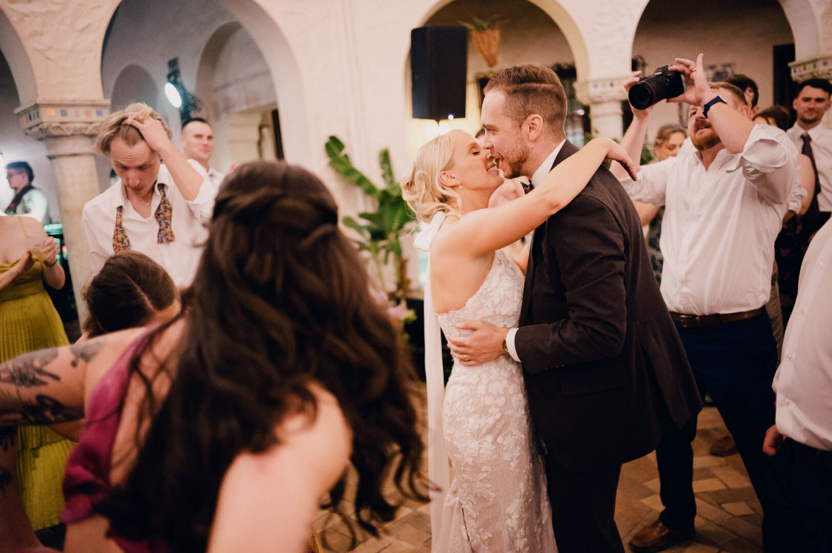 Bride and groom embracing during their first dance at an indoor wedding reception.