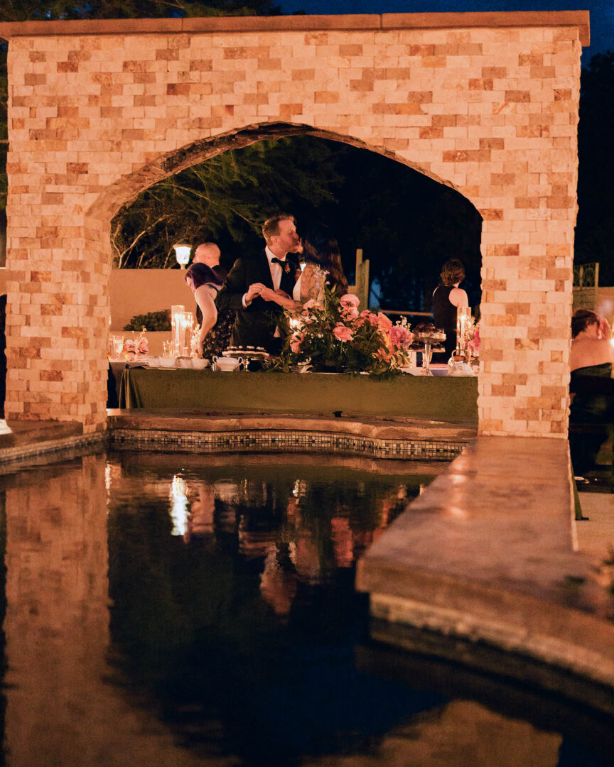 Vibrant Spring Wedding at Shiraz Gardens in Bastrop 69 Evening wedding photo of guests seated by the water and pavilion at Shiraz Gardens in Bastrop, Texas.